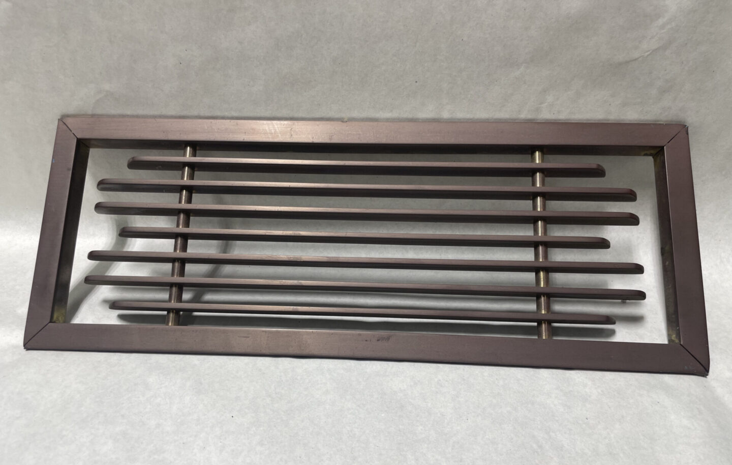 Brown metal vent cover with slats.