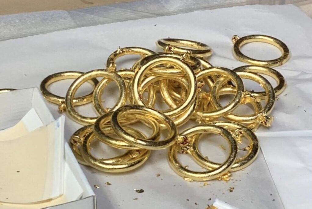 Gold curtain rings on white surface.