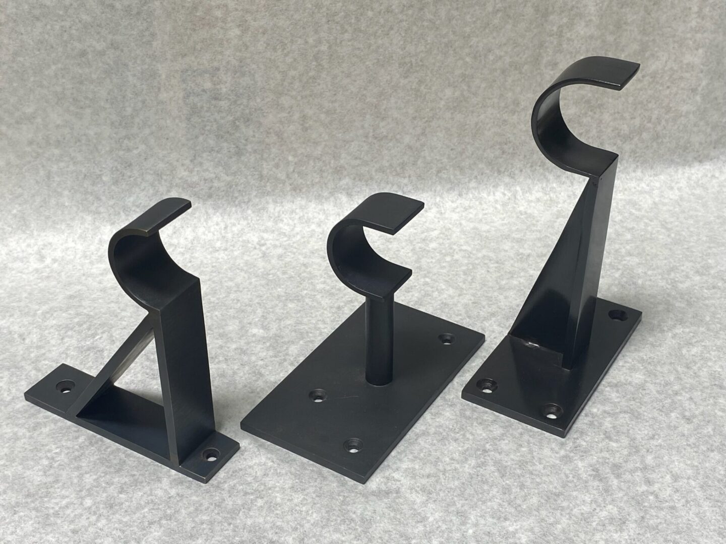 Three black metal curtain rod brackets.